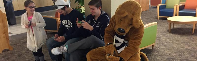 Three kids texting with the Nittany Lion