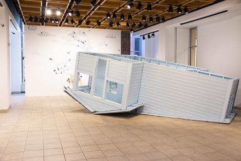 A quarter scale, blue, upside down house in HUB Gallery.
