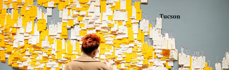 A student standing in front of a wall of toe tags as part of Hostile Terrain 94